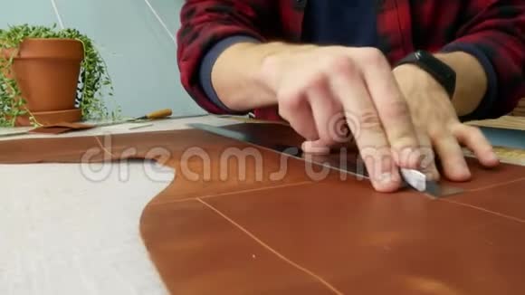 手工皮革工人用一把实用刀切掉额外的一块皮革关门视频的预览图