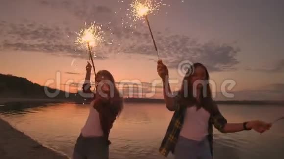 一群朋友女孩和男人在海滩上跳舞在日落时他们慢动作地闪闪发光庆祝新年视频的预览图