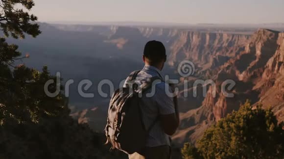 慢动作快乐的年轻商人带着背包徒步旅行在史诗般的夏季日落全景大峡谷视频的预览图