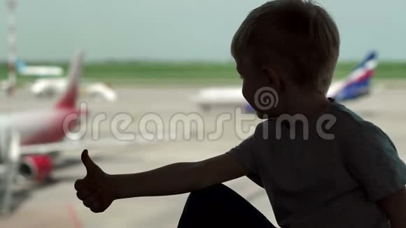 机场窗户附近一个小男孩的轮廓他竖起大拇指视频的预览图