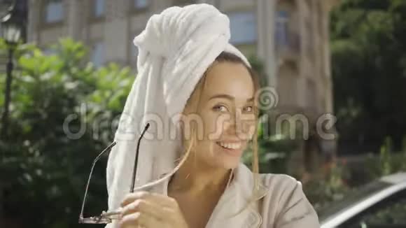 美丽的年轻女子的肖像头上戴着毛巾空中亲吻站在镜头前微笑着看镜头视频的预览图