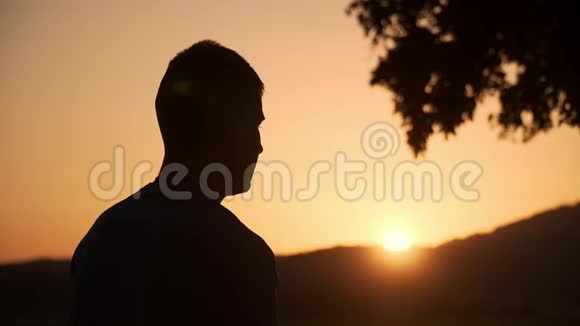 一个男人在美丽的日落中触摸和检查智能手表的Sillhouette背景视频的预览图