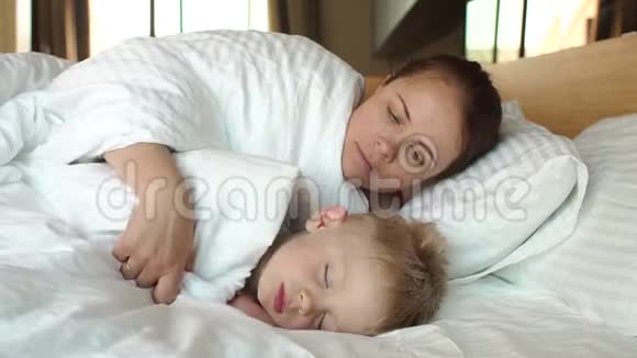 妈妈的特写在床上轻轻地拥抱她熟睡的儿子视频的预览图