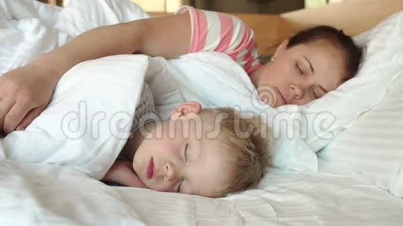 妈妈的特写在床上轻轻地拥抱她熟睡的儿子视频的预览图