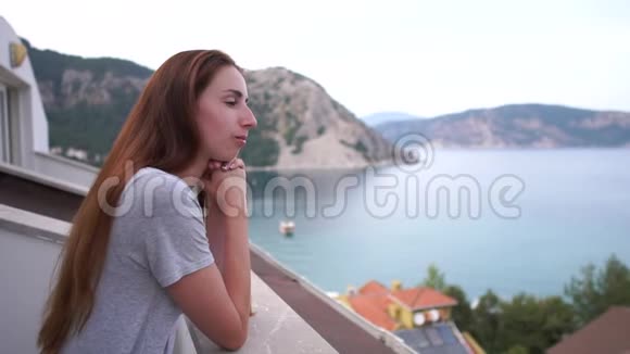 一个女孩从阳台上缓慢地欣赏海景和山景视频的预览图