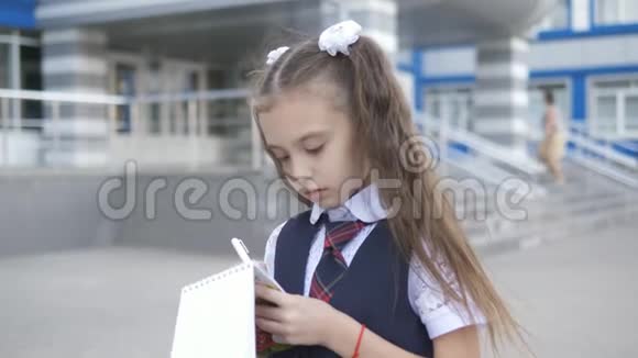 穿校服的以学生为中心的小学在学校大楼附近的笔记本上写或画一些东西视频的预览图