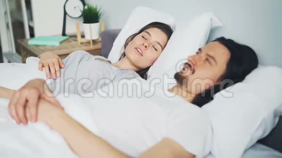 不快乐的男人丈夫用枕头遮住头妻子在床上打鼾视频的预览图