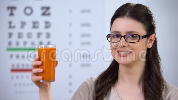 戴眼镜的女人喝新鲜胡萝卜汁背景上的眼睛视觉视频的预览图