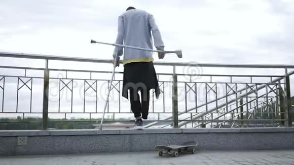 一条腿拄着拐杖的家伙用滑板站在街上残疾人的积极生活这就是视频的预览图