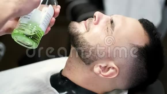 理发师在沙龙里给顾客的脸上注入绿色液体视频的预览图