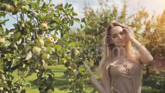 一个美丽的金发女郎走着轻轻地抚摸着苹果树的树枝视频的预览图