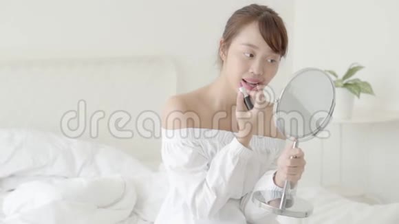 美丽的肖像年轻的亚洲女人在镜子上涂着化妆品口红美丽的女孩时尚的嘴唇视频的预览图