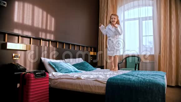 一个小女孩跳在旅馆房间的床上视频的预览图