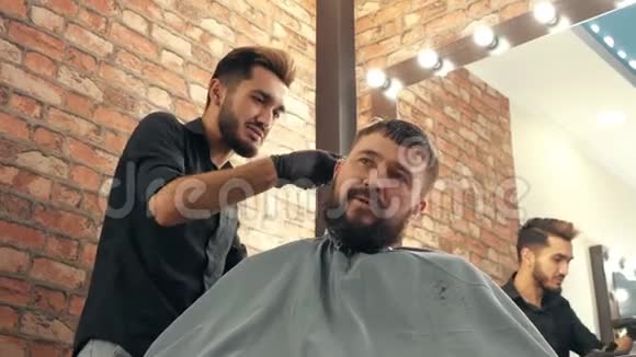 在理发店里微笑理发师修剪和胡须客户交谈视频的预览图