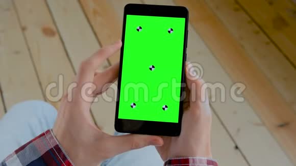 男子手持黑色智能手机与空白绿色屏幕色度关键概念视频的预览图