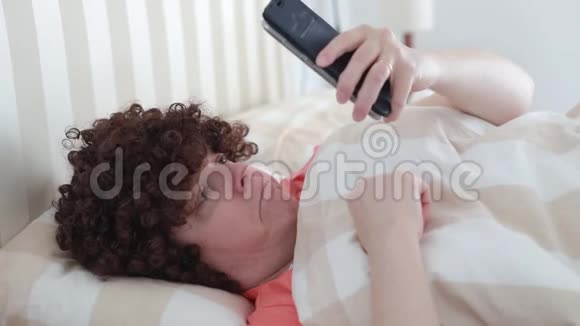 穿着粉红色衣服躺在床上的中年妇女视频的预览图