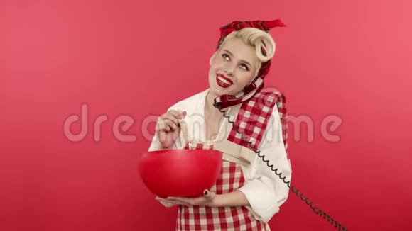 兴奋地把女人用粉色背景在电话上做饭和交谈视频的预览图