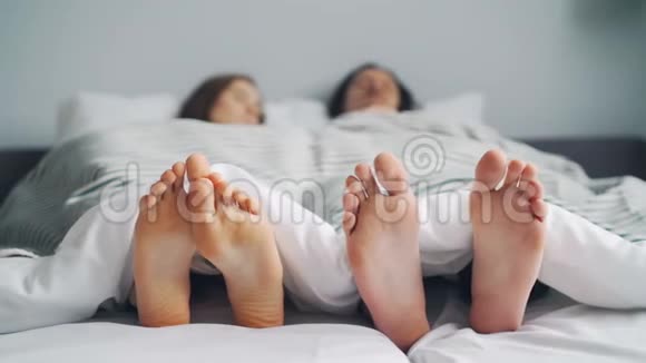 丈夫和妻子睡在床上躺在毯子下双脚集中视频的预览图