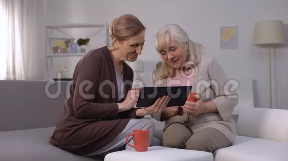 老年妇女面带微笑在平板电脑上观看娱乐节目快速上网视频的预览图