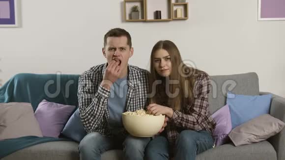 焦点夫妻看电视用沮丧的表情把爆米花扔到镜头里视频的预览图
