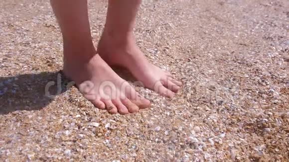 光着脚的女人度假时在贝壳沙滩上按摩她的脚视频的预览图