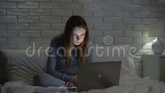 深夜上网的苍白的女孩看上去精疲力竭沉迷于网络视频的预览图