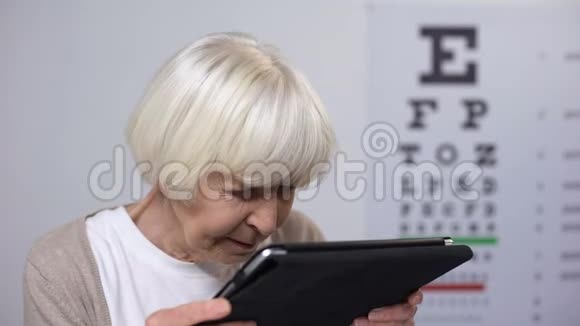 年老的女士戴上眼镜微笑着从平板电脑上阅读聚焦视力视频的预览图