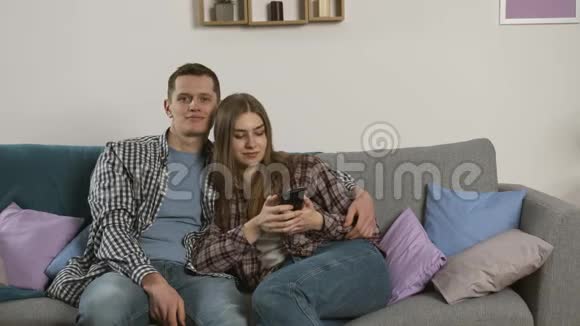 微笑情侣一起使用智能手机看电视视频的预览图