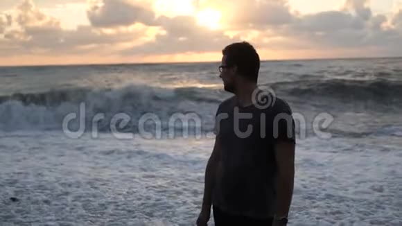 一个虔诚的人看着波涛汹涌的海浪看着如诗如画的日落在格鲁吉亚的斯洛文尼亚视频的预览图