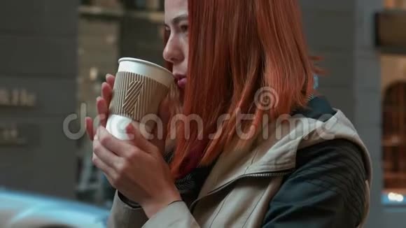 有着狐臭头发的女孩在街上的纸杯里喝茶视频的预览图