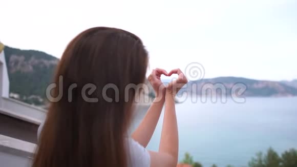 一个女孩在大海的背景下慢慢地用手做了一个心形视频的预览图