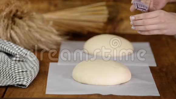贝克为烤箱准备面包女人把融化的黄油刷在生面包上视频的预览图