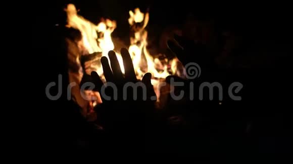 人们的手在营火中取暖露营开火夜间手部轮廓视频的预览图