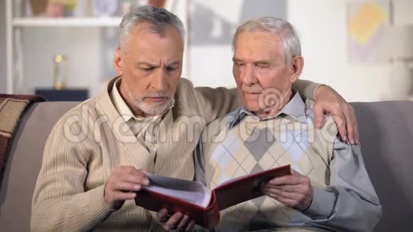 老父亲和太阳在家里沙发上看家庭相册在一起特写视频的预览图