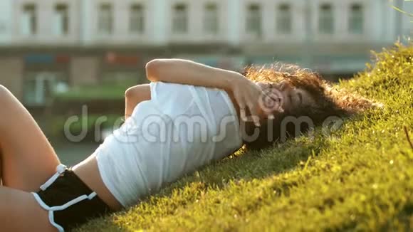漂亮的瘦小女人躺在草地上用手拥抱自己然后站起来视频的预览图