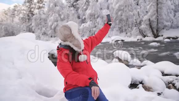 冬河附近山上的美丽女孩在智能手机上自拍微笑视频的预览图