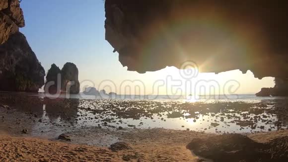 热带岛屿上壮丽的日落从石窟到大海的景色和一条阳光明媚的小路船的轮廓勒夫视频的预览图