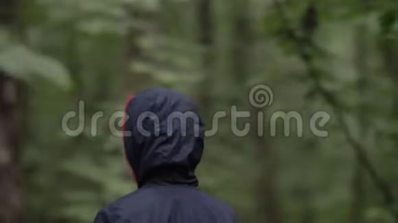 晚上穿着夹克和头罩的男孩在户外穿过森林视频的预览图