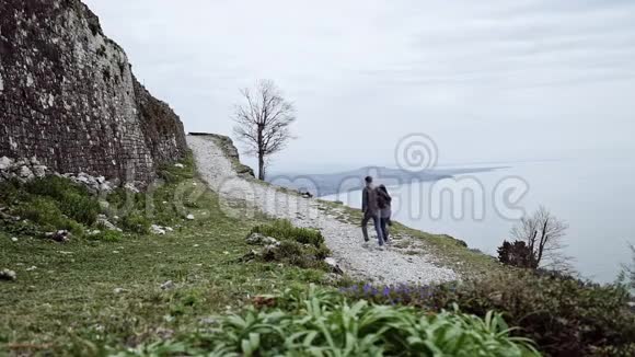 恋爱中的情侣在海和山的背景下沿着悬崖边的小路散步玩得很开心视频的预览图