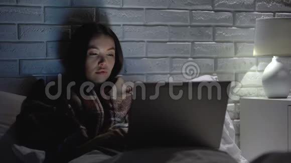 女孩打喷嚏很厉害晚上躺在床上用笔记本电脑看电影流感症状视频的预览图