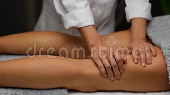 美丽的年轻女子在水疗中心接受抗纤维素按摩按摩师做专业的腿部按摩视频的预览图