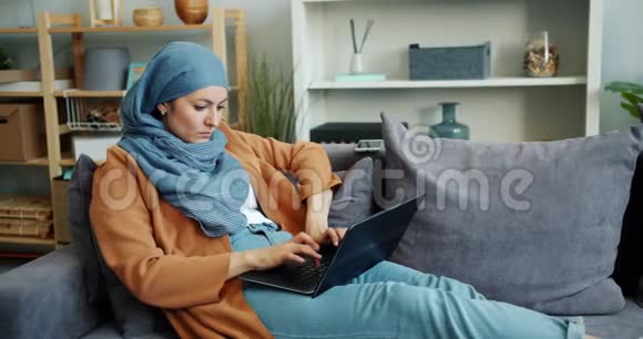 独立的穆斯林女孩在公寓里用手提电脑打字忙着工作视频的预览图