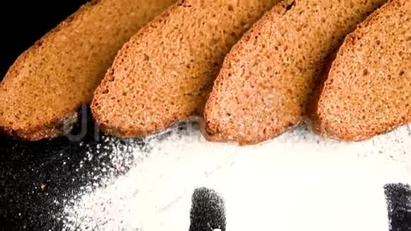 白色小麦粉上的铭文面包店黑色背景上的切片黑麦面包视频的预览图