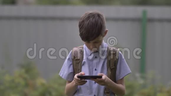 带背包的男孩在户外用电话上学视频的预览图