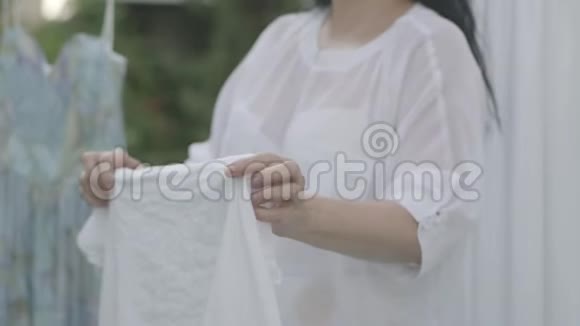 未被识别的成熟女人拿着柳条篮子在户外晾白衣服洗衣日视频的预览图