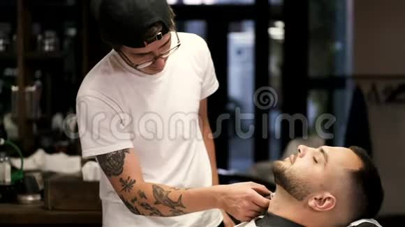 理发店的理发师戴着黑色的帽子剪客户的胡子视频的预览图
