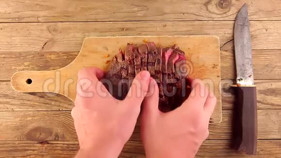 男人的手露出用旧刀放在木板上的烤牛肉片视频的预览图