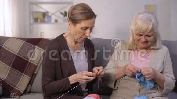 老年妇女学习与她成熟和有经验的朋友编织爱好视频的预览图
