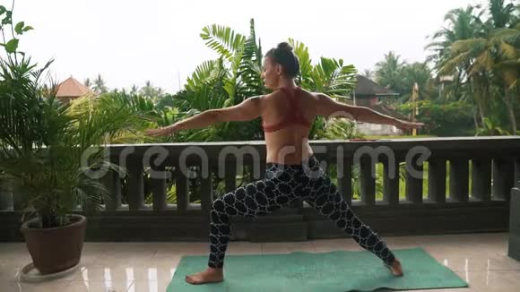 健身妇女在阳台上练习瑜伽背景是棕榈树视频的预览图