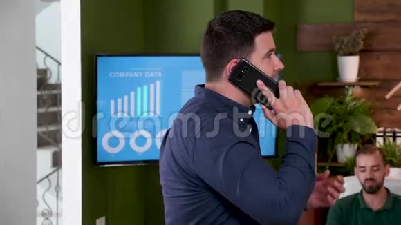 商人在办公室里散步时打电话视频的预览图